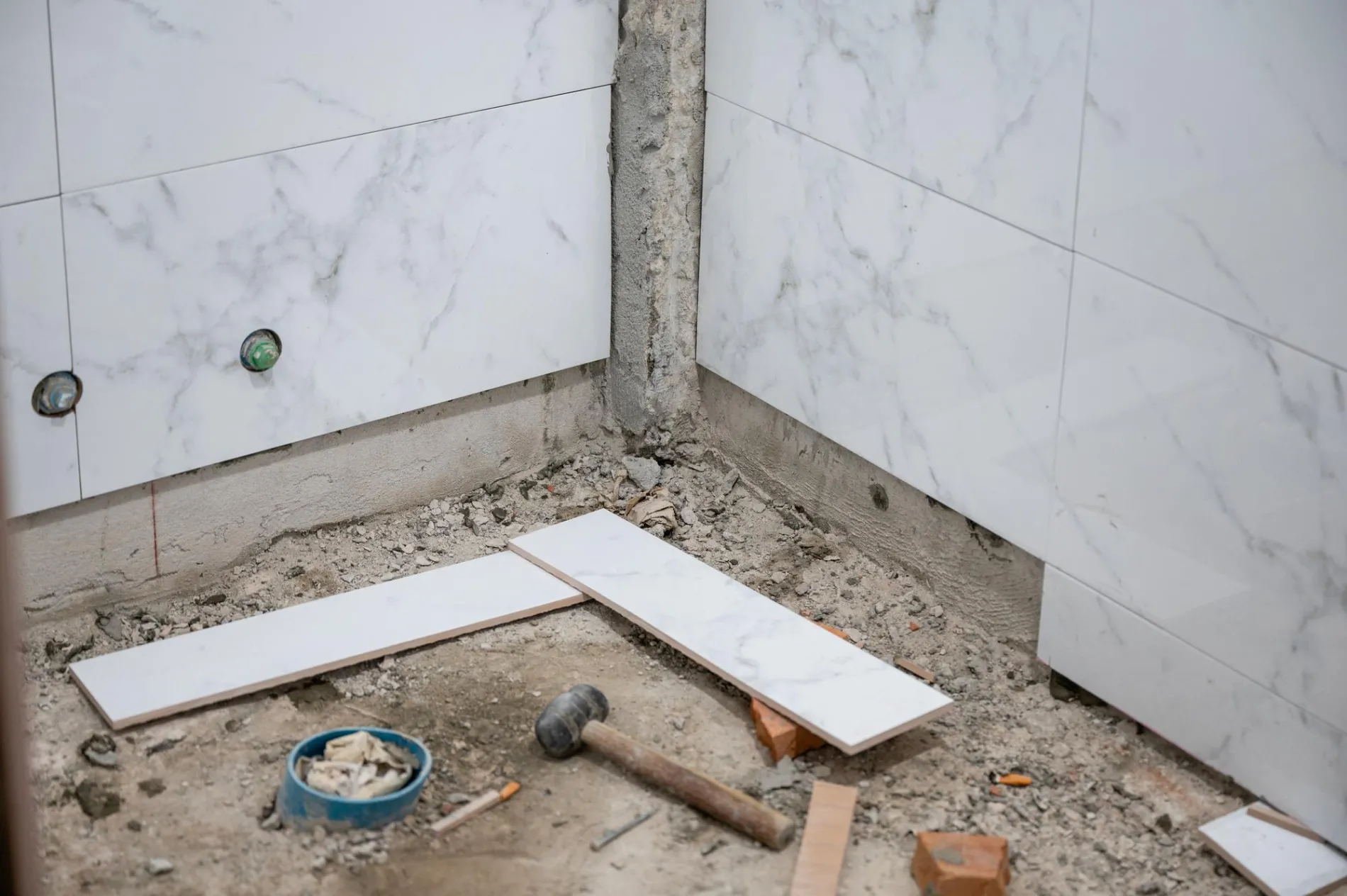 Artisan posant une natte d'étanchéité orange pour une douche à l'italienne.